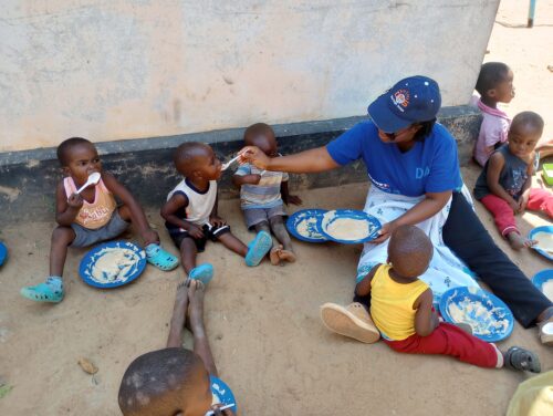Young children sitting on the ground at one of the children feeding programs in Zimbabwe.